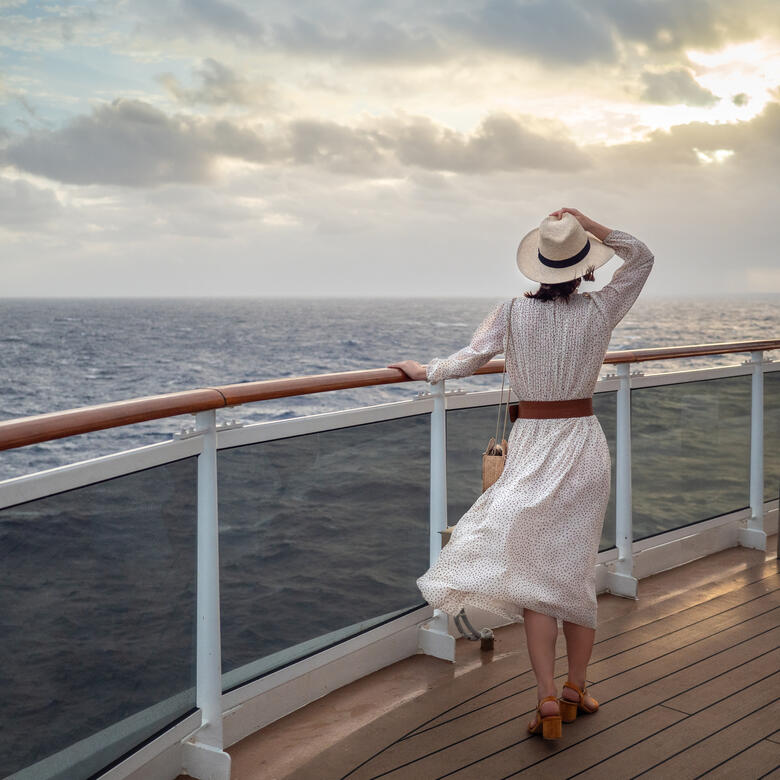 Female traveler from Rockford, IL standing on a cruise ship deck, gazing at the ocean.